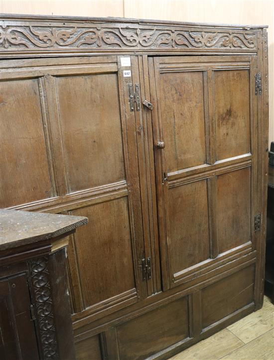 A 17th century oak carved and panelled two door hanging cupboard, W.150cm (a.f.)